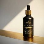Black serum bottle with dropper labeled 'bellah ROZE' on a reflective surface with soft lighting.