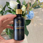 Hand hold hair growth oil in luxury black and gold packaging 